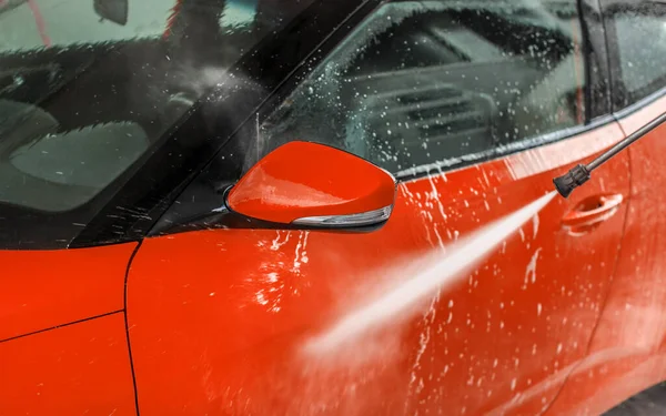 Bright red car washed in self serve carwash, detail on high pres — Stock Photo, Image