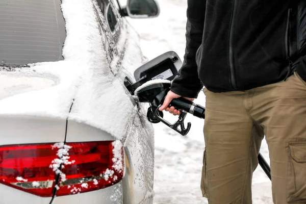 Homme remplissant son réservoir d'essence de voiture diesel recouvert de neige au pum carburant — Photo