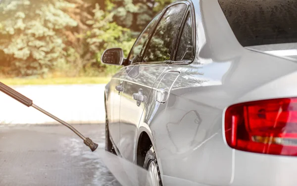 Silver car washed in self serve carwash, jet water spraying from — Stock Photo, Image