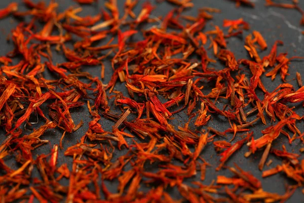 Bright red orange dried saffron (Crocus sativus) flowers on blac — Stock Photo, Image