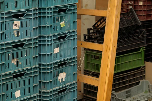 Scatole di plastica impilate in magazzino, scala in legno e più contenitori sullo sfondo — Foto Stock