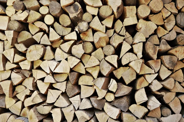 Wooden logs cut to pieces stacked as firewood near house — Stock Photo, Image