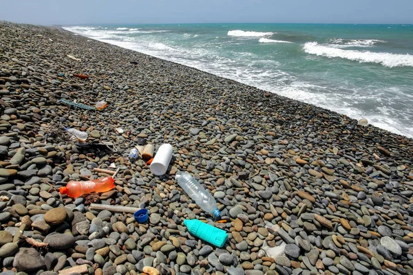 Plastic bottles rubbish on wild pebbles beach. Ocean and sea littering concept