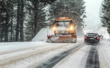 Liptovsky Hradok, Slovakya - 08 Ocak 2019: Kar fırtınasında orman yolunda turuncu bakım kamyonu. Bu bölgedeki yollar kışın tehlikeli olur.. 