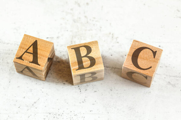 Three wooden cubes with letters ABC - stands for Always Be Closing - on white board.