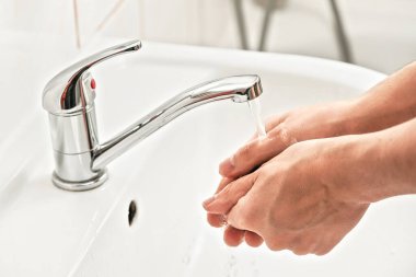Musluğun altında ellerini yıkayan bir adam. Kişisel hijyen kavramı, covid-19 koronavirüs salgınında kullanılabilir