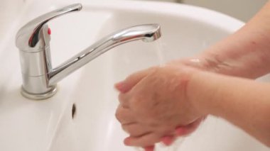 Yaşlı yaşlı bir kadın musluğun altında ellerini sabunla yıkıyor. Ncov coronavirus / covid-19 salgını önleme sürecinde hijyen illüstrasyon kavramı olarak kullanılabilir