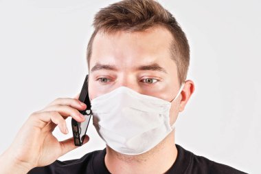 Evde takılan genç adam cep telefonuyla konuşan pamuk suratlı burun virüs maskesi takıyor. Stüdyo portresi, beyaz arkaplan - Coronavirus covid-19 salgını sırasında kullanılabilir