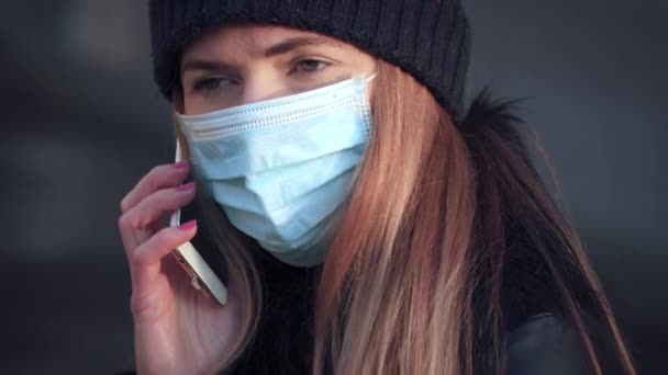 身穿一次性蓝色病毒口罩的年轻女子在手机上说话 闭锁细节 可用于Coronavirus Covid 19疾病的预防 — 图库视频影像