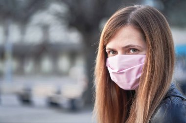 El yapımı burun maskeli genç bir kadın. Arkasındaki boş şehir meydanını bulanıklaştırmış. Coronavirus covid-19 salgını önleme sırasında kullanılabilir
