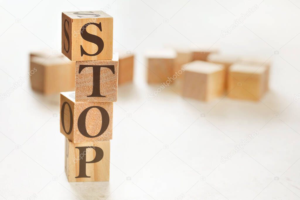 Four wooden cubes arranged in stack with word STOP on them, space for text image at down right corner