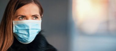Tek kullanımlık mavi virüs takan genç bir kadın ağız maskesi, yakın plan portre, yazı için yeri olan pankart. Coronavirus covid-19 salgın önleme kavramı