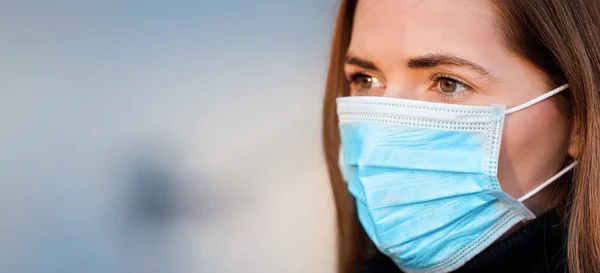 使い捨ての青いウイルスを身に着けている若い女性は口の鼻マスク クローズアップ肖像画に直面している テキストの左側のためのスペースと広いバナー コロナウイルス Covid 19発生防止コンセプト — ストック写真
