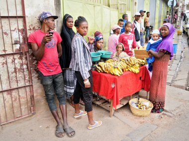 Antananarivo, Madagaskar - 24 Nisan 2019: Sokakta muz satan bir kadının yanında duran bilinmeyen bir grup Malagasy 'li. Ülke fakirdir ve yerel halk genellikle süpermarketlerden alışveriş yapamaz.