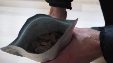 Gümüş plastik poşetin üzerinde organik çiğ çikolata parçaları var.