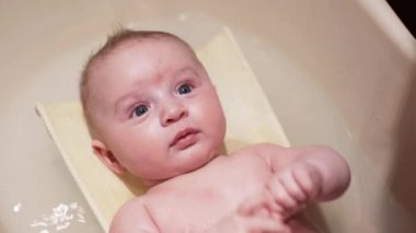 Bebek bebek banyo yapıyor, annesi onunla oynuyor, kafasında detay var, yukarıdan bakıyor.