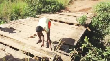 Sendrisoa, Madagaskar - 28 Nisan 2019: Bilinmeyen yerel Malagasy adamları tahta tahtaları hareket ettirerek köprüyü tamir ediyorlar, böylece araba geçebiliyor. Bu bölgede yollar berbat durumda, özellikle yağmurdan sonra.