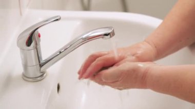 Yaşlı yaşlı bir kadın musluğun altında ellerini sabunla yıkıyor. Ncov coronavirus / covid 19 salgını önleme sürecinde hijyen illüstrasyon kavramı olarak kullanılabilir