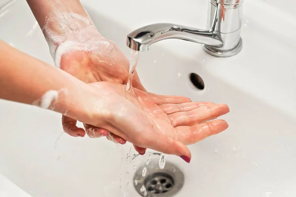 Wanita muda mencuci tangannya di bawah air keran keran dengan sabun. Detail pada cairan di atas kulit. Soap suds di pergelangan tangan, konsep kebersihan pribadi — Stok Foto