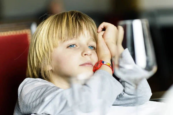 Ernstige kind alleen aan tafel zit — Stockfoto