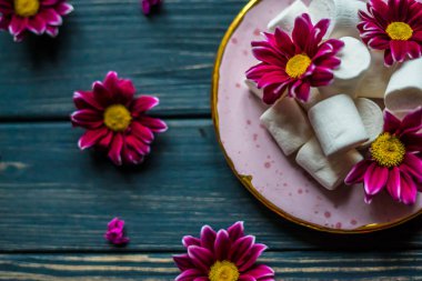 Kırmızı çiçekler ve marshmallow ahşap bir masa üzerinde