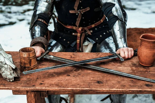 Man at the table with two swords — Stock Photo, Image