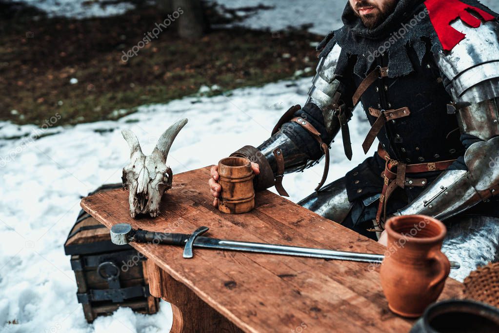 man in armor at a wooden table
