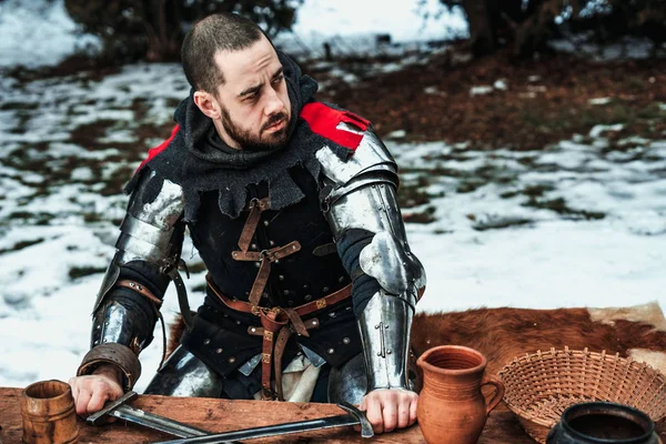 Male knight sits at a wooden table — Stock Photo, Image