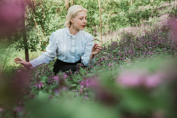Chica en el jardín recoge hierbas y olfatea flores — Foto de Stock