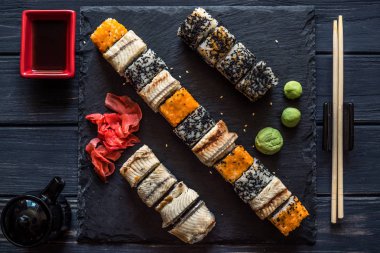 suşi, sauceboat, soya sosu, turşu zencefil, susam ve çanak çömlek siyah ahşap zemin seti