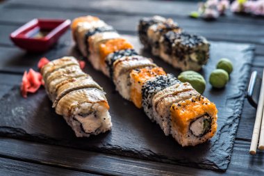 suşi, sauceboat, soya sosu, turşu zencefil, susam ve çanak çömlek siyah ahşap zemin seti