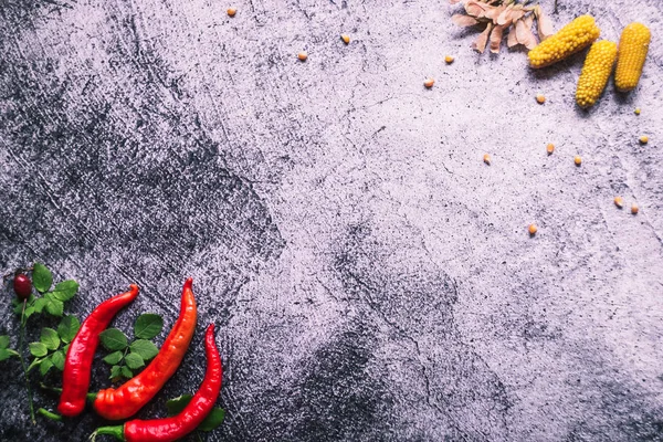 La pimienta roja caliente con hojas verdes y maíz se encuentra en un cesto gris. —  Fotos de Stock
