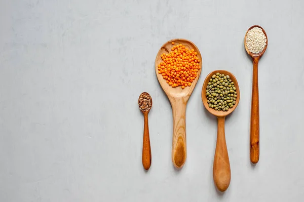 Handmade spoons made of wood. Close-up of wooden spoons with lentils and other grains.