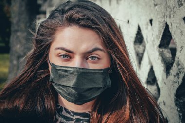 Kız, yüzünde koruyucu steril tıbbi maske takan genç bir kadın Asya sokak gösterilerinde, avuçlarında, ellerinde kameralara bakıyor. Hava kirliliği, virüs, Çin salgını koronavirüs konsepti.