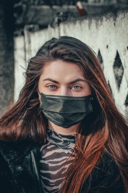 Kız, yüzünde koruyucu steril tıbbi maske takan genç bir kadın Asya sokak gösterilerinde, avuçlarında, ellerinde kameralara bakıyor. Hava kirliliği, virüs, Çin salgını koronavirüs konsepti.