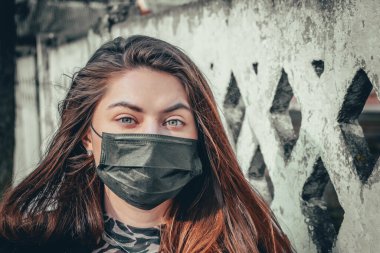 Kız, yüzünde koruyucu steril tıbbi maske takan genç bir kadın Asya sokak gösterilerinde, avuçlarında, ellerinde kameralara bakıyor. Hava kirliliği, virüs, Çin salgını koronavirüs konsepti.