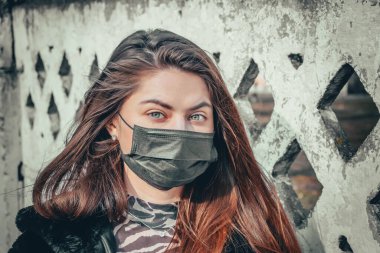 Kız, yüzünde koruyucu steril tıbbi maske takan genç bir kadın Asya sokak gösterilerinde, avuçlarında, ellerinde kameralara bakıyor. Hava kirliliği, virüs, Çin salgını koronavirüs konsepti.