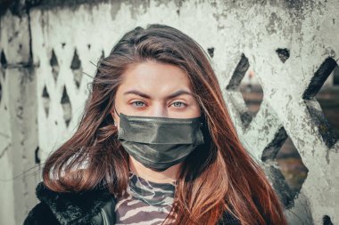 Kız, yüzünde koruyucu steril tıbbi maske takan genç bir kadın Asya sokak gösterilerinde, avuçlarında, ellerinde kameralara bakıyor. Hava kirliliği, virüs, Çin salgını koronavirüs konsepti.