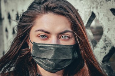 Kız, yüzünde koruyucu steril tıbbi maske takan genç bir kadın Asya sokak gösterilerinde, avuçlarında, ellerinde kameralara bakıyor. Hava kirliliği, virüs, Çin salgını koronavirüs konsepti.