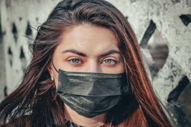 Kız, yüzünde koruyucu steril tıbbi maske takan genç bir kadın Asya sokak gösterilerinde, avuçlarında, ellerinde kameralara bakıyor. Hava kirliliği, virüs, Çin salgını koronavirüs konsepti.