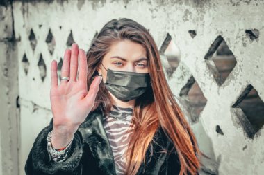 Kız, yüzünde koruyucu steril tıbbi maske takan genç bir kadın Asya sokak gösterilerinde, avuçlarında, ellerinde kameralara bakıyor. Hava kirliliği, virüs, Çin salgını koronavirüs konsepti.