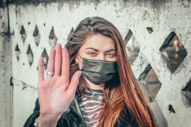 Kız, yüzünde koruyucu steril tıbbi maske takan genç bir kadın Asya sokak gösterilerinde, avuçlarında, ellerinde kameralara bakıyor. Hava kirliliği, virüs, Çin salgını koronavirüs konsepti.