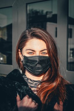 Kız, yüzünde koruyucu steril tıbbi maske takan genç bir kadın Asya sokak gösterilerinde, avuçlarında, ellerinde kameralara bakıyor. Hava kirliliği, virüs, Çin salgını koronavirüs konsepti.