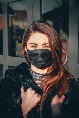 Kız, yüzünde koruyucu steril tıbbi maske takan genç bir kadın Asya sokak gösterilerinde, avuçlarında, ellerinde kameralara bakıyor. Hava kirliliği, virüs, Çin salgını koronavirüs konsepti.