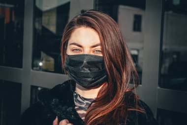 Kız, yüzünde koruyucu steril tıbbi maske takan genç bir kadın Asya sokak gösterilerinde, avuçlarında, ellerinde kameralara bakıyor. Hava kirliliği, virüs, Çin salgını koronavirüs konsepti.