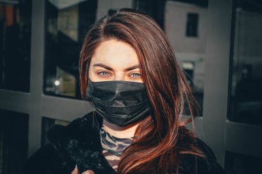 Kız, yüzünde koruyucu steril tıbbi maske takan genç bir kadın Asya sokak gösterilerinde, avuçlarında, ellerinde kameralara bakıyor. Hava kirliliği, virüs, Çin salgını koronavirüs konsepti.