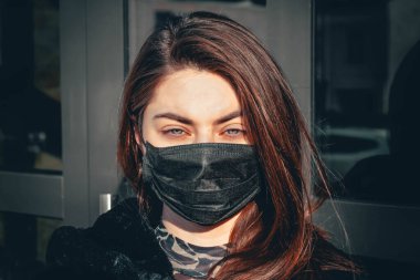 Kız, yüzünde koruyucu steril tıbbi maske takan genç bir kadın Asya sokak gösterilerinde, avuçlarında, ellerinde kameralara bakıyor. Hava kirliliği, virüs, Çin salgını koronavirüs konsepti.