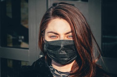 Kız, yüzünde koruyucu steril tıbbi maske takan genç bir kadın Asya sokak gösterilerinde, avuçlarında, ellerinde kameralara bakıyor. Hava kirliliği, virüs, Çin salgını koronavirüs konsepti.