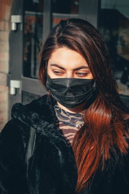 Kız, yüzünde koruyucu steril tıbbi maske takan genç bir kadın Asya sokak gösterilerinde, avuçlarında, ellerinde kameralara bakıyor. Hava kirliliği, virüs, Çin salgını koronavirüs konsepti.