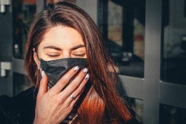 Kız, yüzünde koruyucu steril tıbbi maske takan genç bir kadın Asya sokak gösterilerinde, avuçlarında, ellerinde kameralara bakıyor. Hava kirliliği, virüs, Çin salgını koronavirüs konsepti.